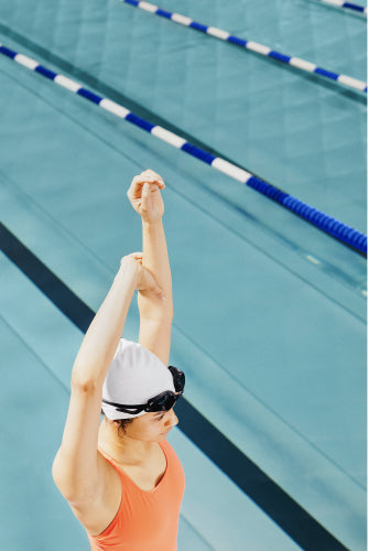 Woman stretching in front of a swimming pool